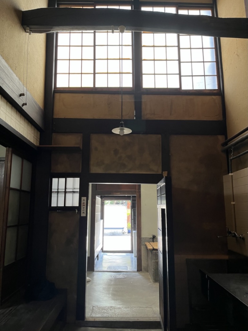 土間の先に開いた戸口から、家の奥へ光が届く。